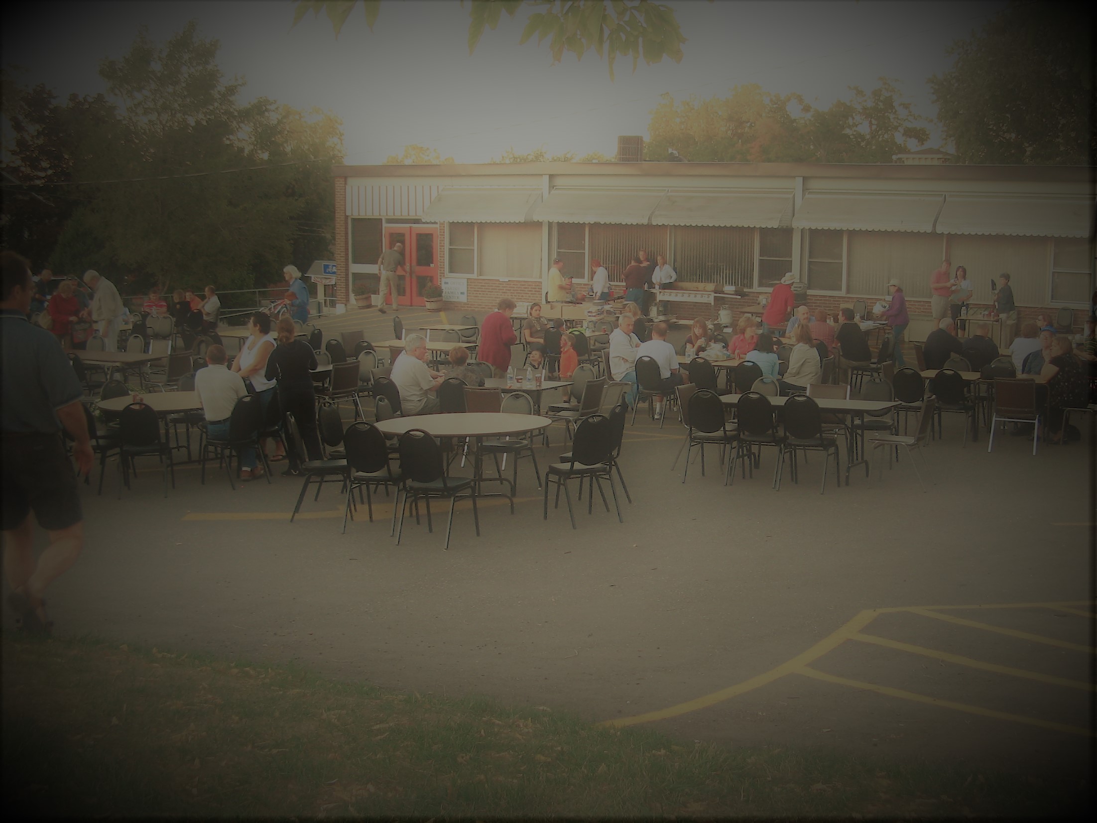 An outdoor social gathering of parishioners on the parish office parking lot