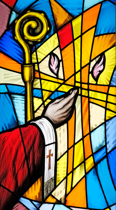 A picture of a stain glass window. it depicts a bishop, with his crozier, celebration Confirmation.